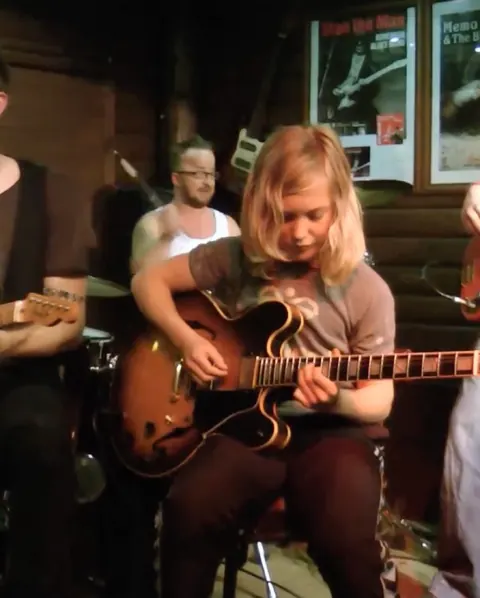 Oscar som ung musiker med el-guitar på en scene